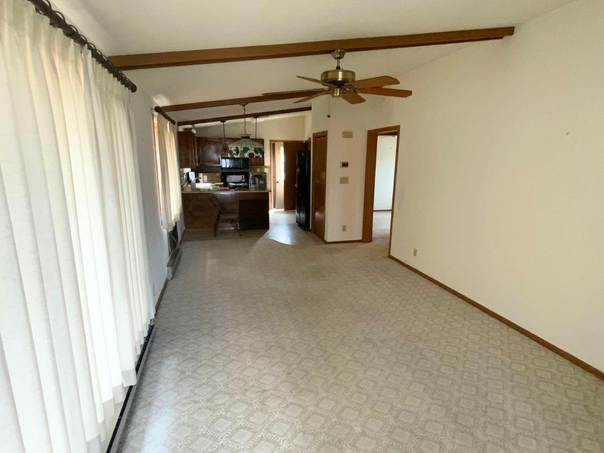 An empty living room with a ceiling fan