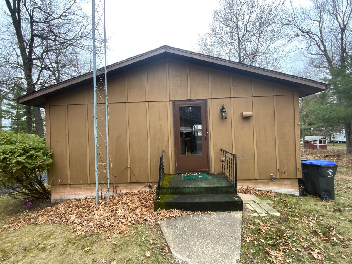 A small brown house with a ladder on the side of it.