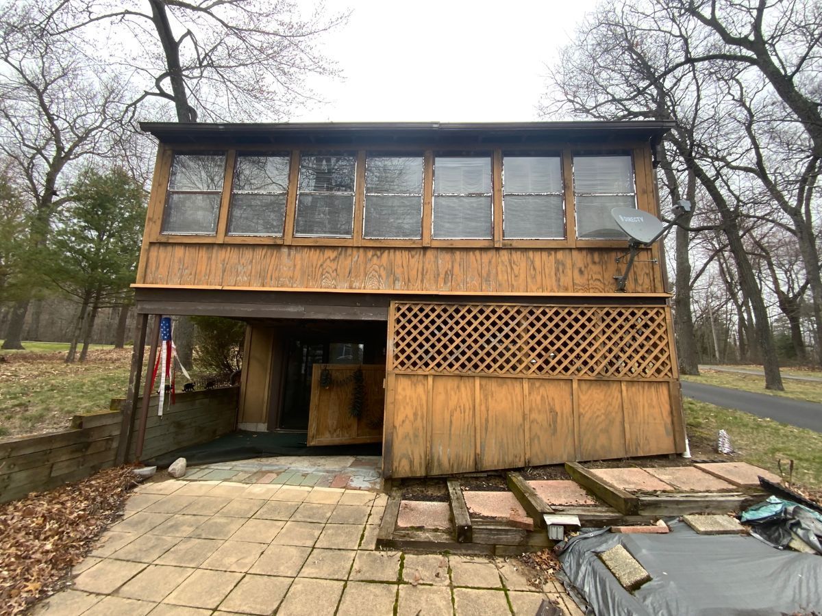 A small wooden house with a lot of windows is sitting in the middle of a forest.