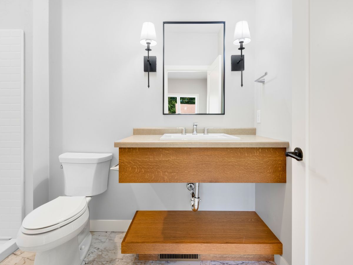A bathroom with a toilet , sink and mirror.