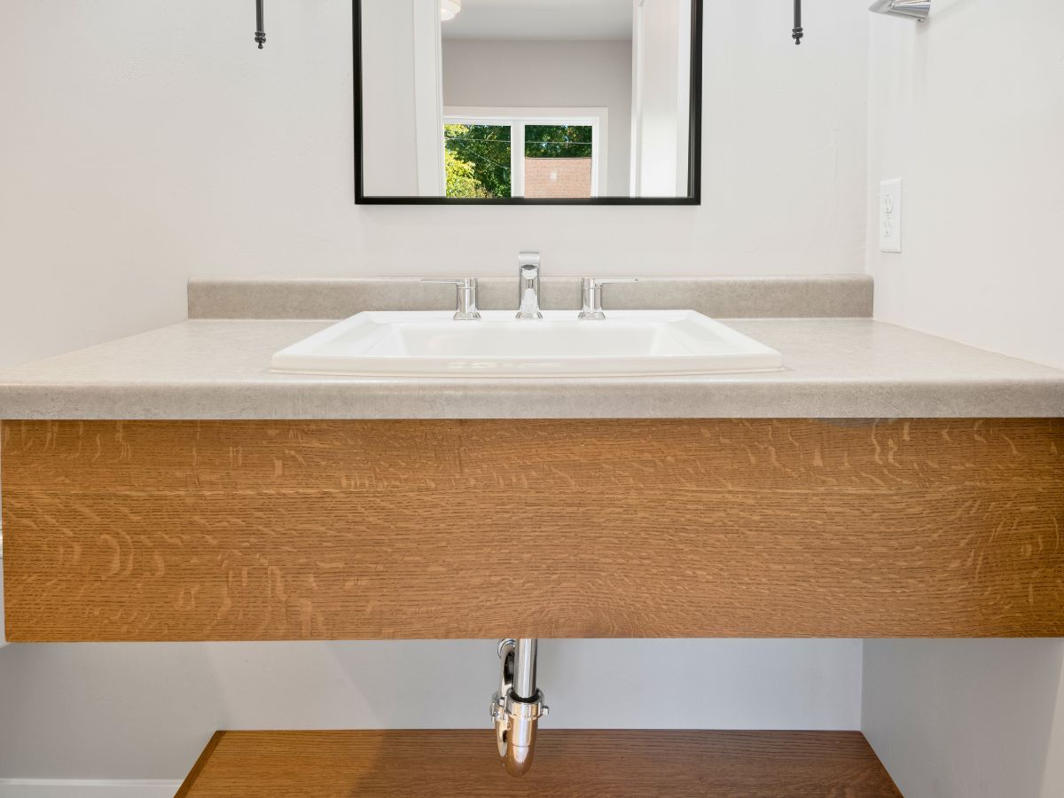 A bathroom sink with a wooden counter top and a mirror.