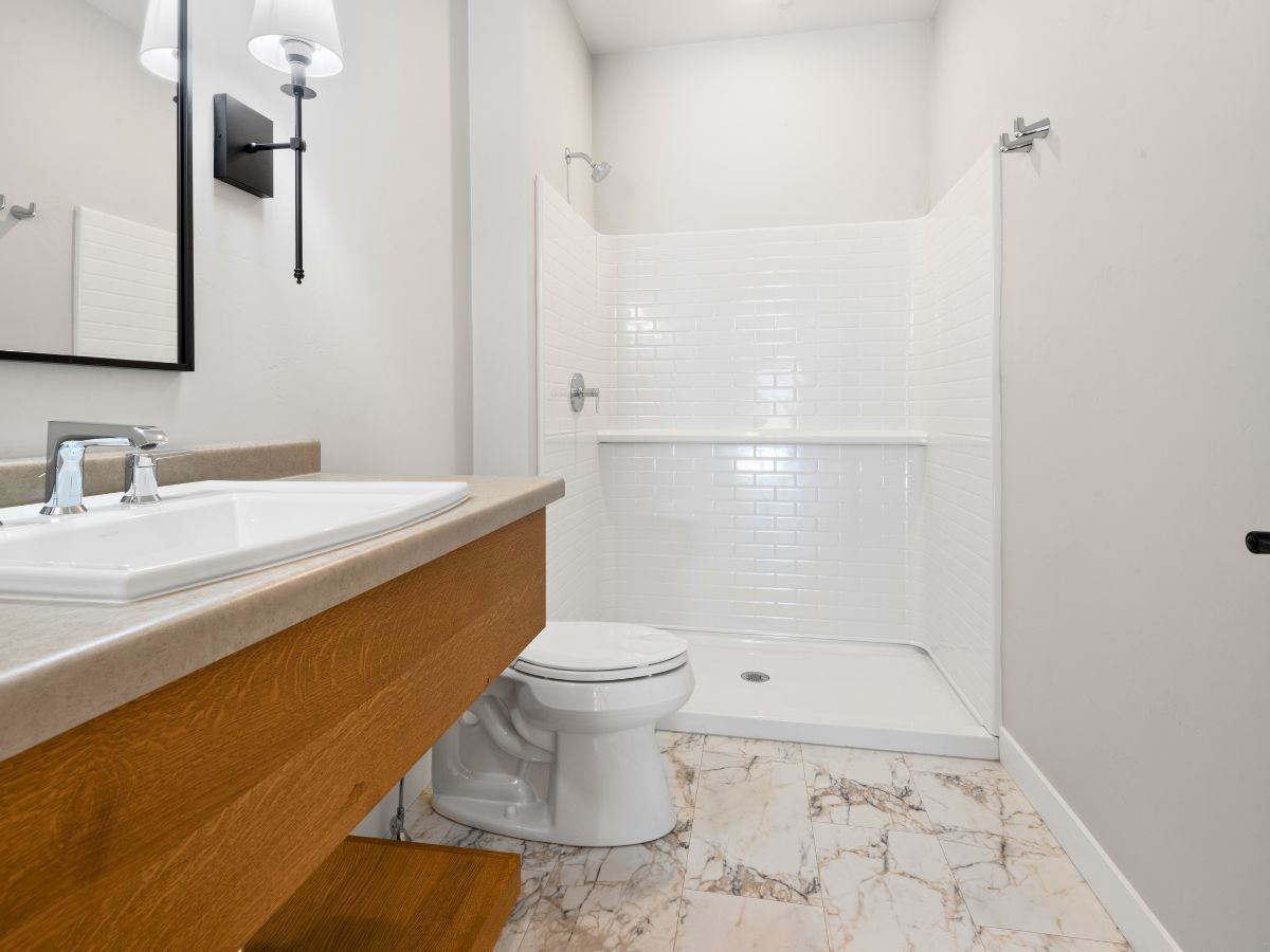 A bathroom with a toilet , sink and shower.
