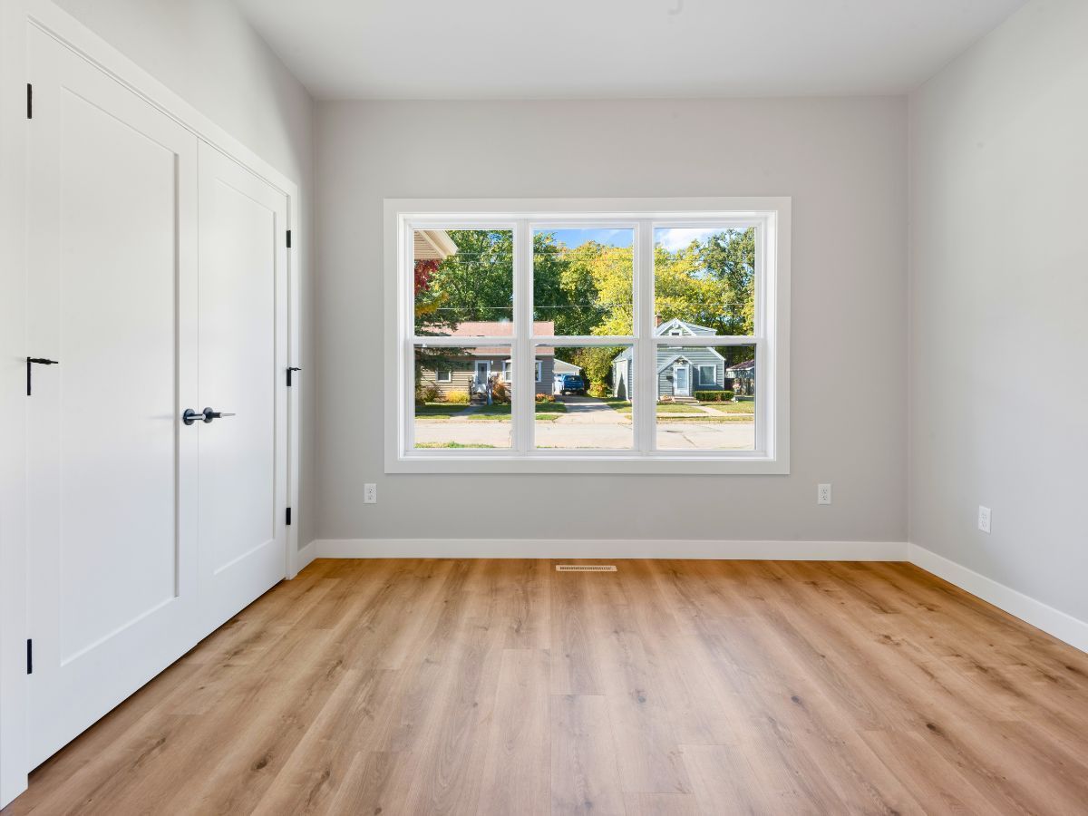 An empty room with hardwood floors and a large window.