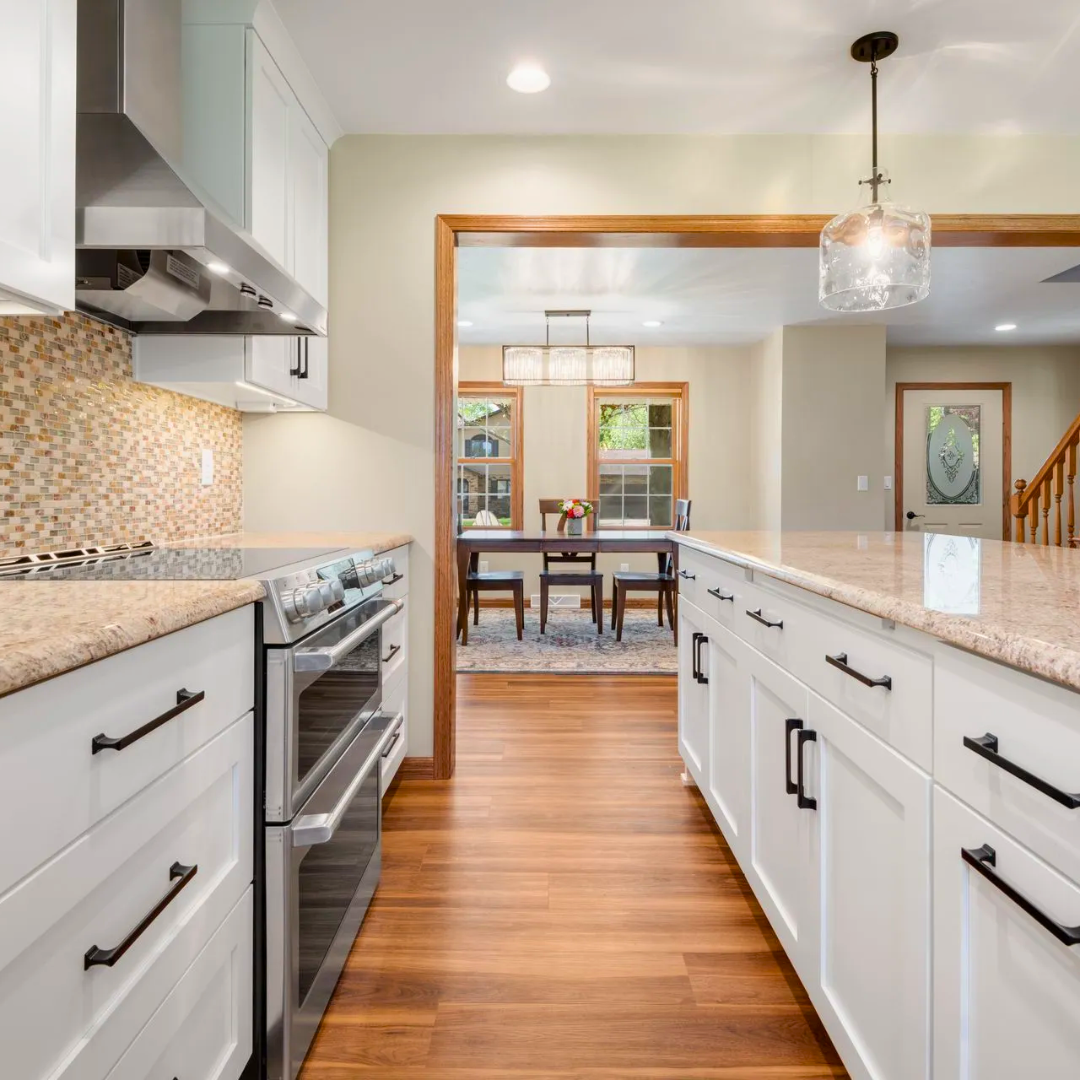 A kitchen with white cabinets , stainless steel appliances , granite counter tops and hardwood floors.