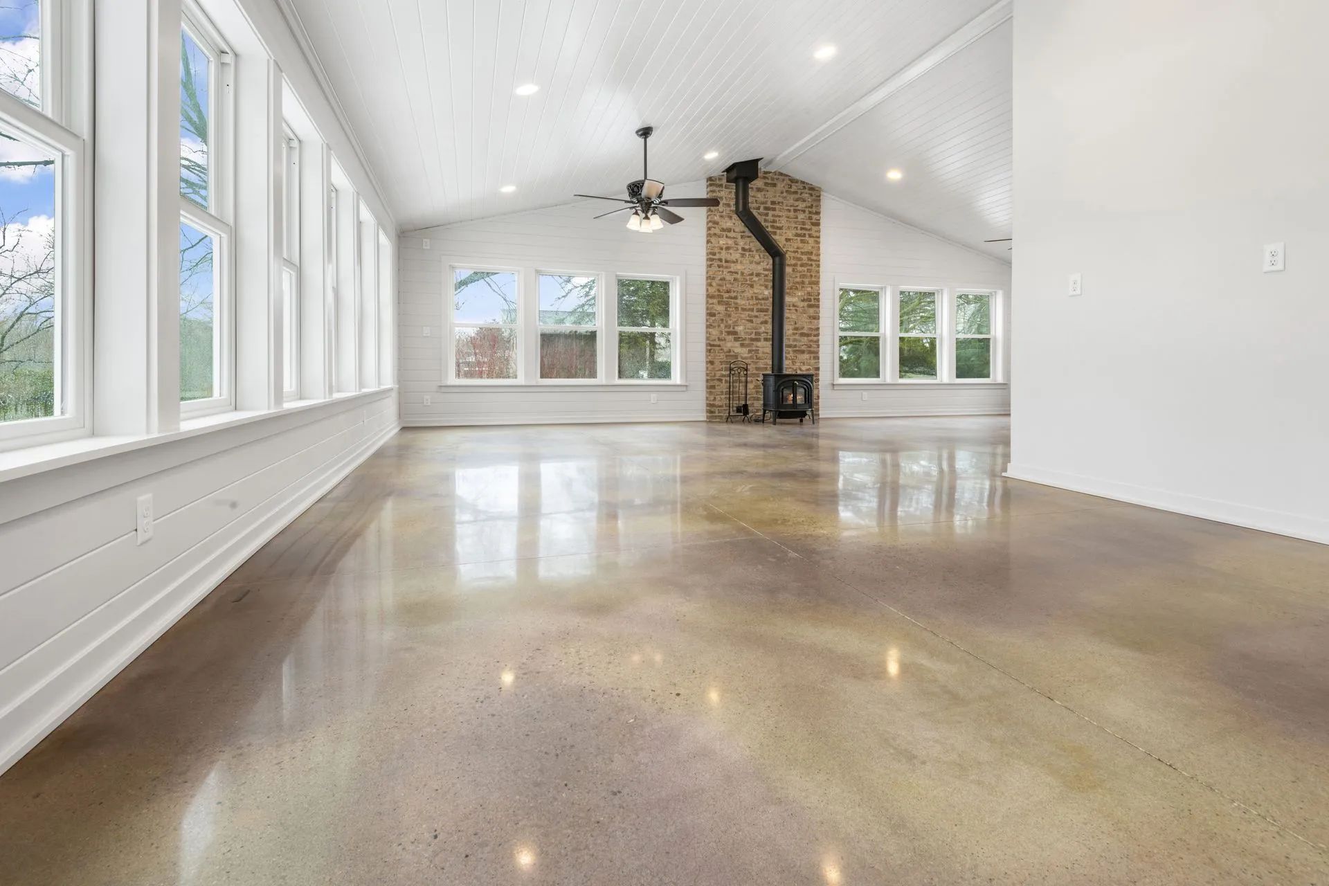 An empty living room with a ceiling fan and a fireplace.