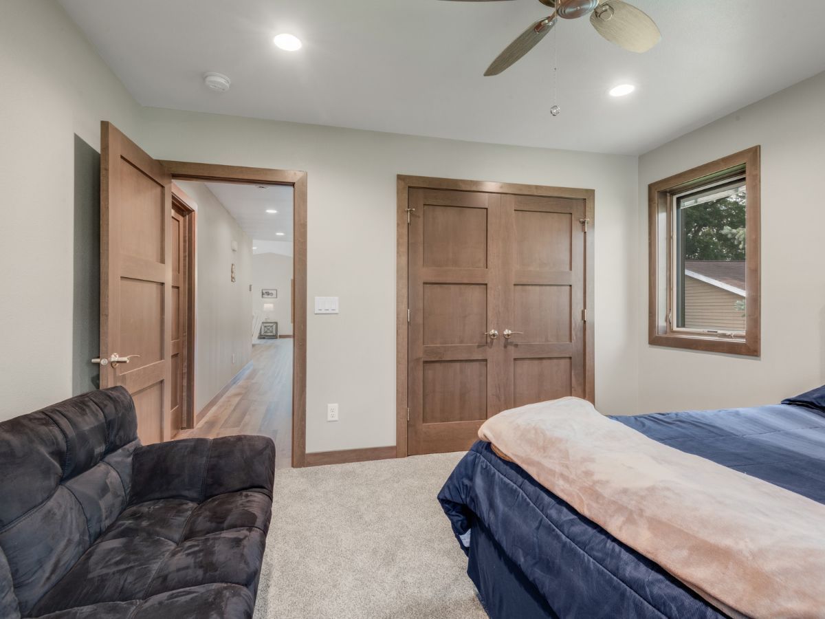 A bedroom with a bed , couch , and ceiling fan.