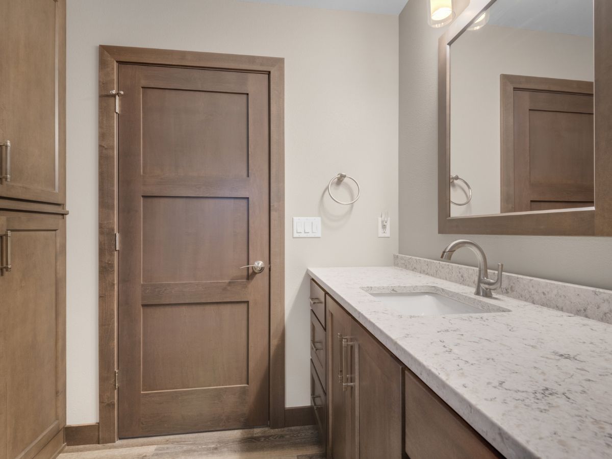 A bathroom with a sink , mirror and wooden cabinets