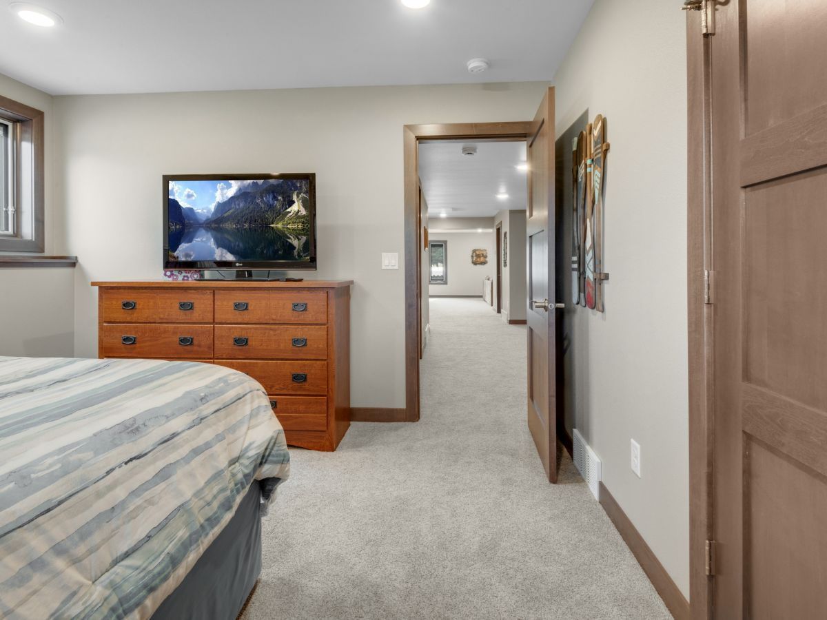 A bedroom with a bed a dresser and a flat screen tv