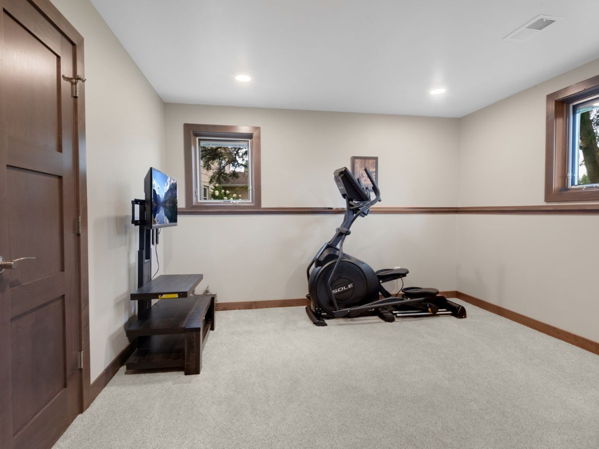 A room with a elliptical and a flat screen tv