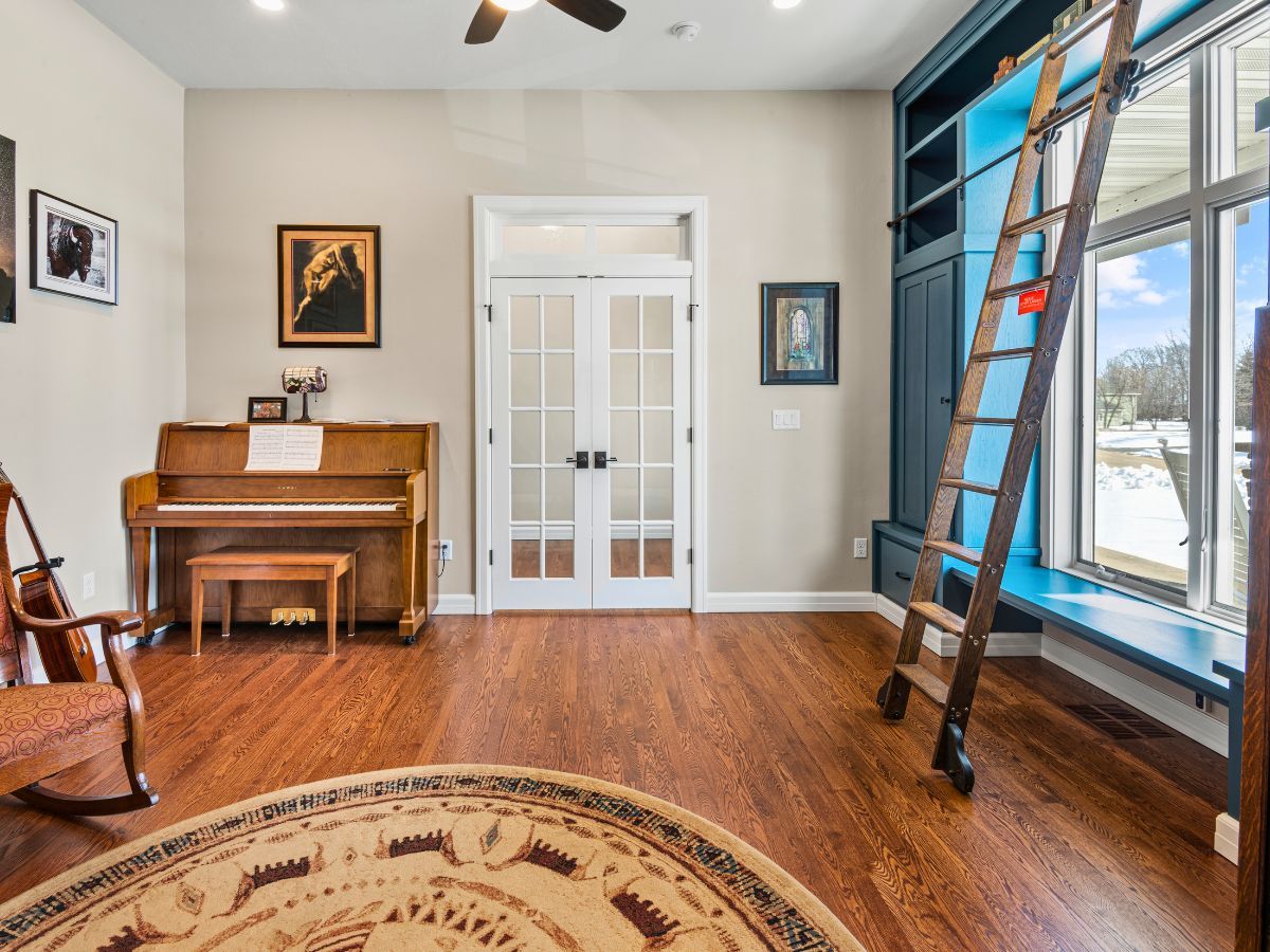 A living room with a piano , rocking chair , and ladder.