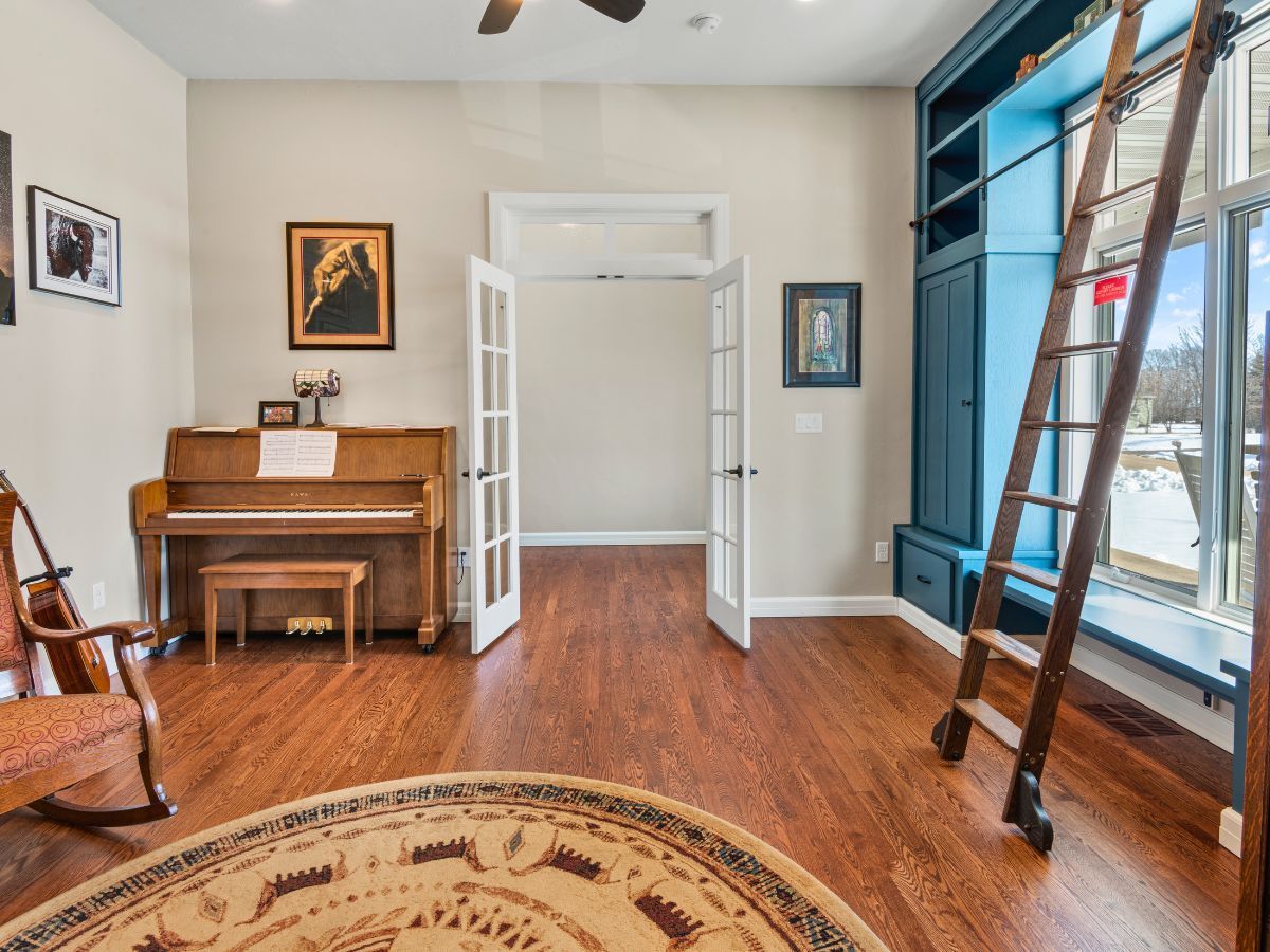 A living room with a piano , rocking chair , and ladder.