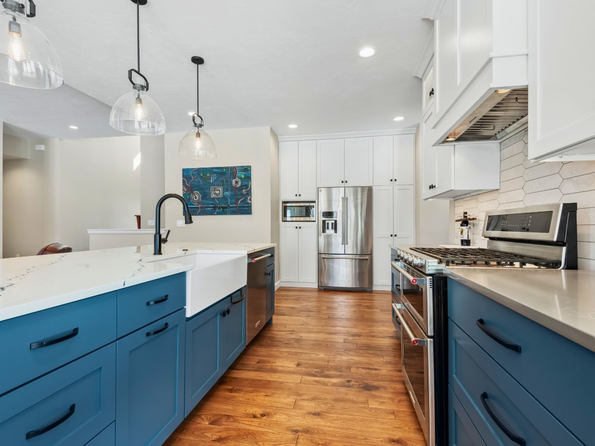 A kitchen with blue cabinets , white cabinets and stainless steel appliances.