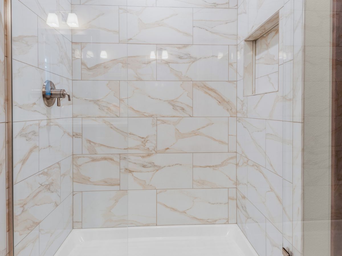 A bathroom with marble tiles and a walk in shower.