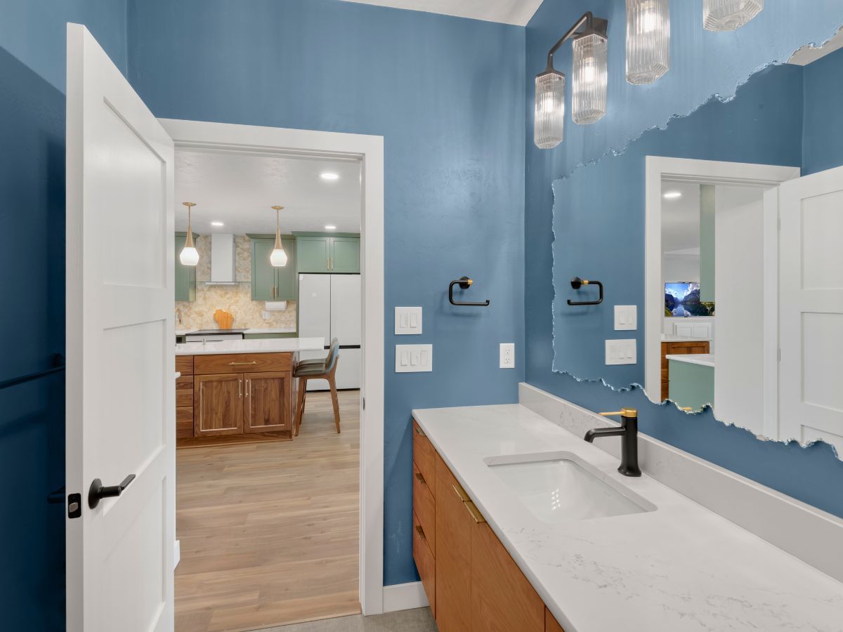 A bathroom with blue walls , a sink and a mirror.