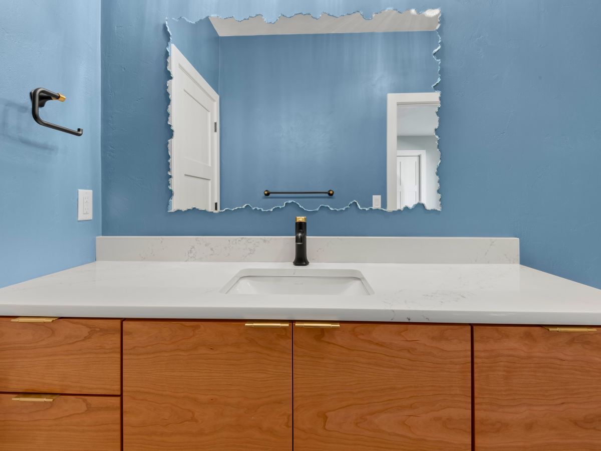 A bathroom with a sink , mirror and blue walls.