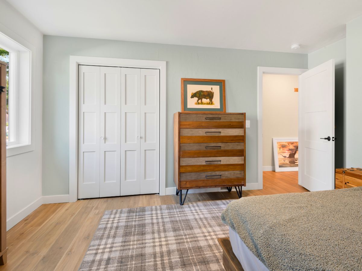A bedroom with a bed , dresser , and picture on the wall.