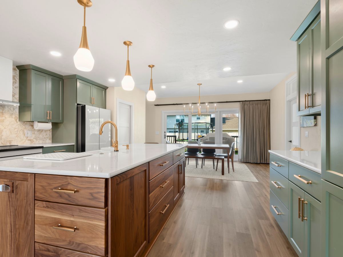 A kitchen with green cabinets and a large island in the middle.