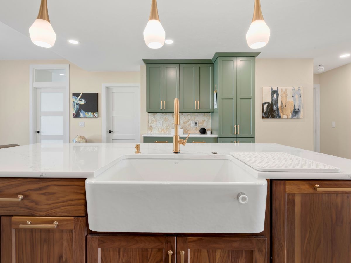 A kitchen with a large white sink and wooden cabinets.