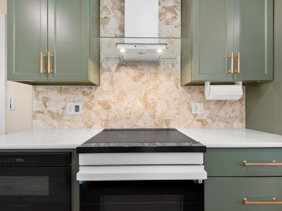 A kitchen with green cabinets , black appliances , and a stove top oven.