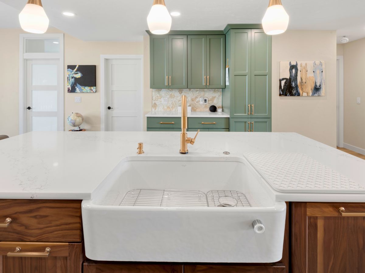 A kitchen with a large white sink and green cabinets.