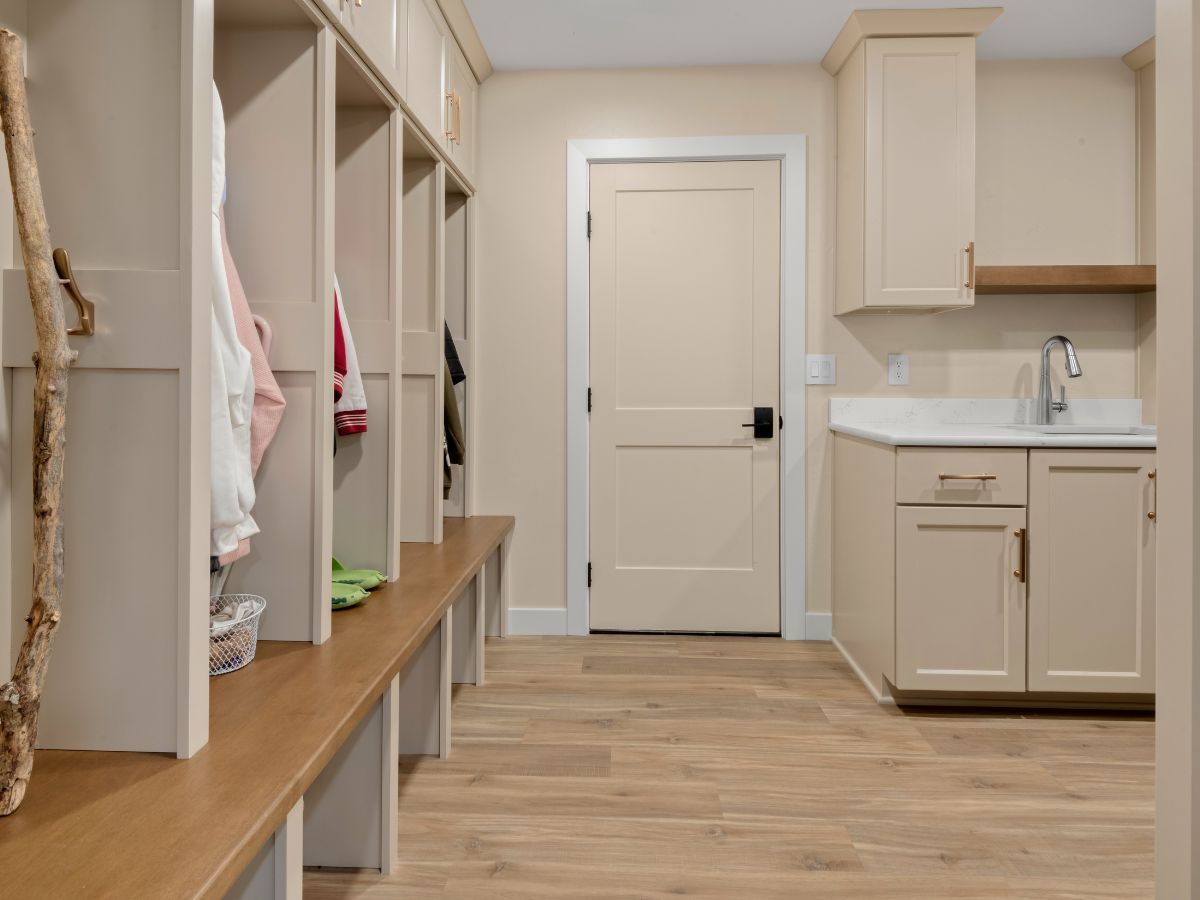 A laundry room with white cabinets and a sink