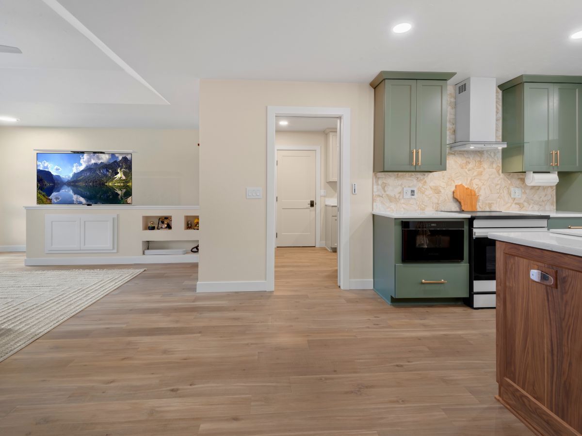 A kitchen with green cabinets and a flat screen tv on the wall