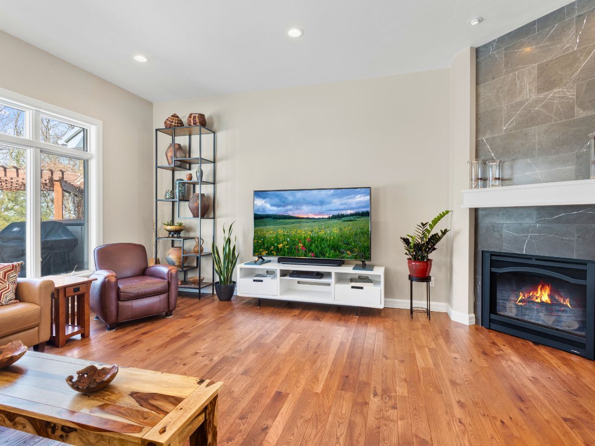 A living room with hardwood floors , a fireplace and a flat screen tv.
