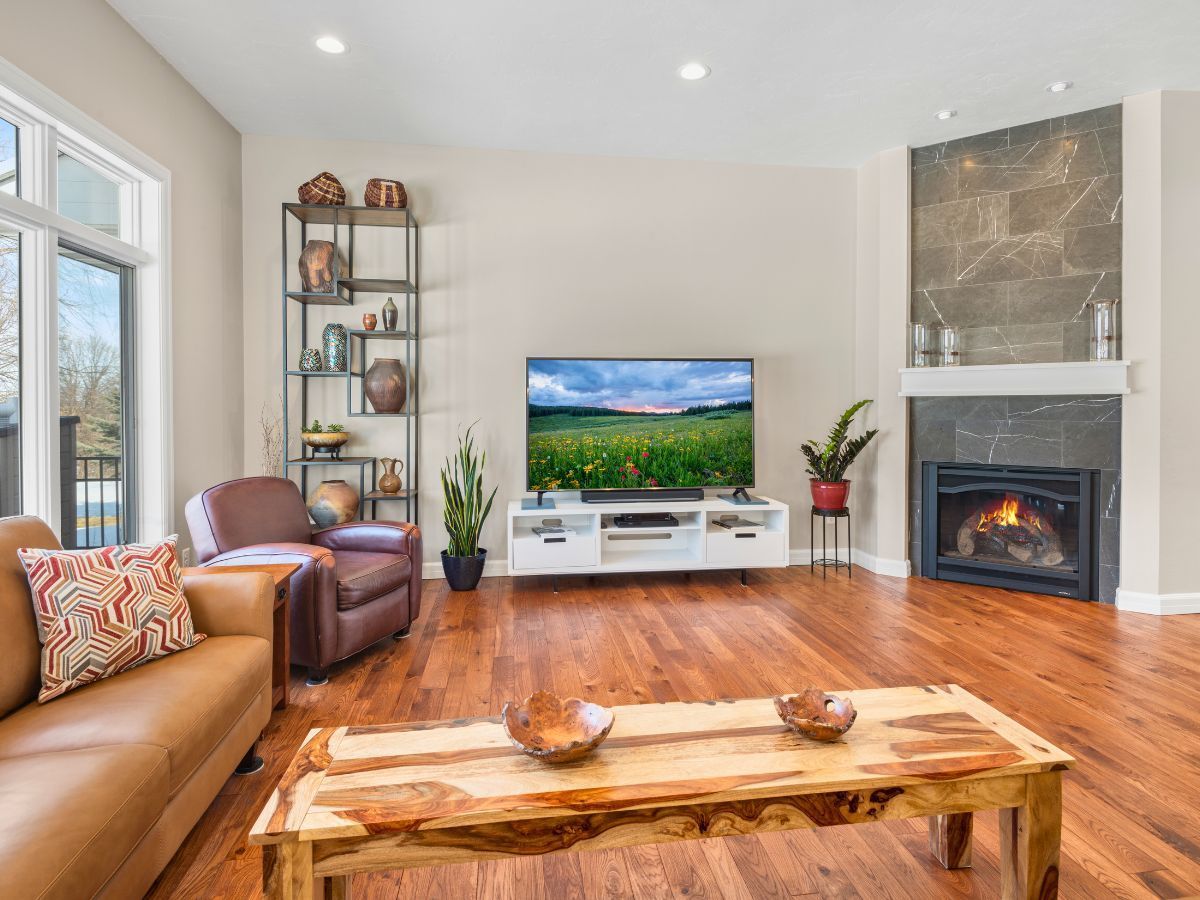 A living room with hardwood floors , a fireplace and a flat screen tv.