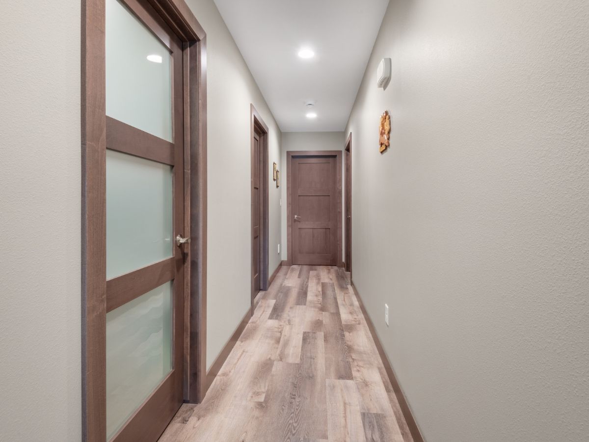 A long hallway with wooden floors and glass doors.