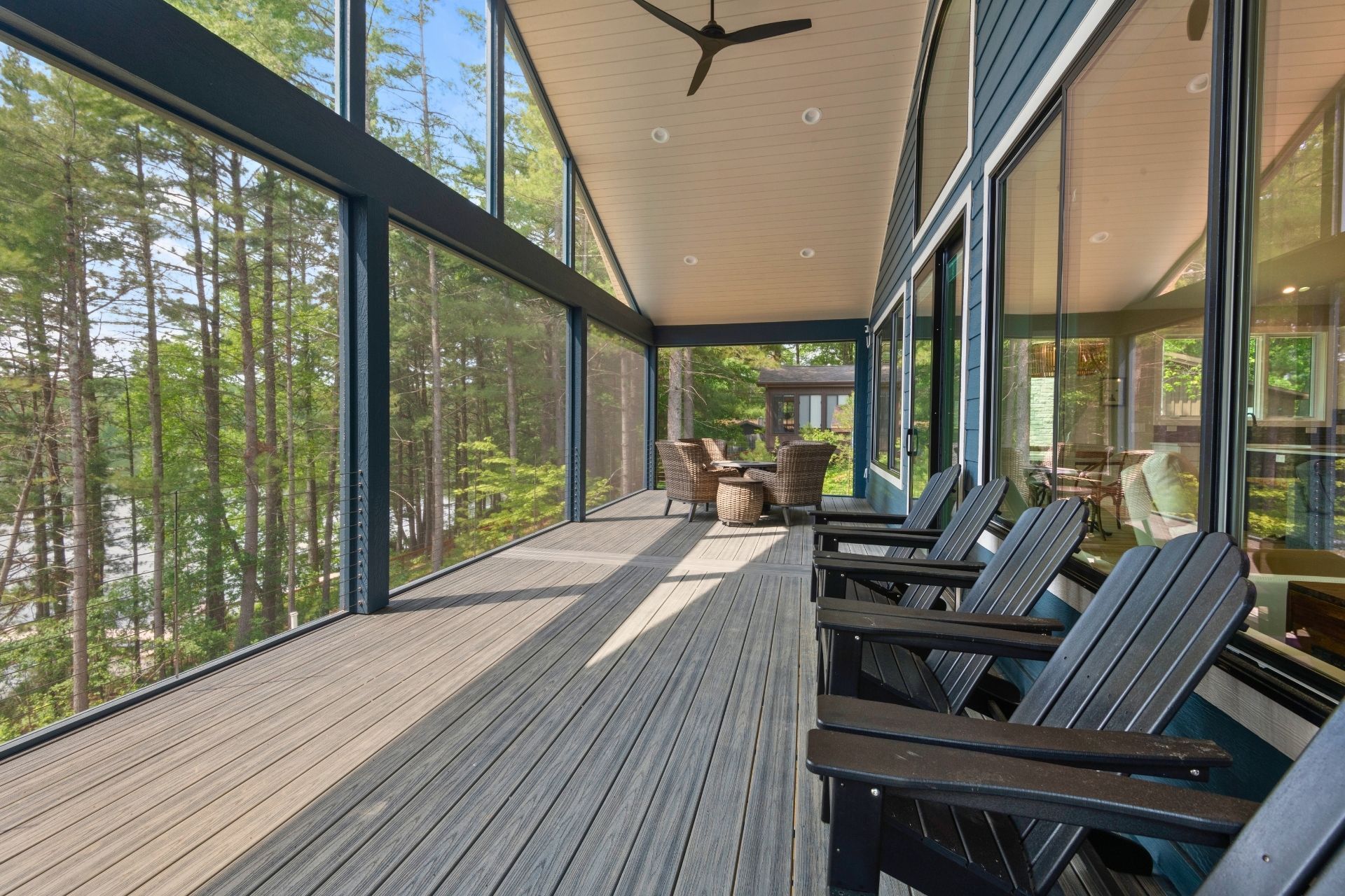 A screened in porch with chairs and a ceiling fan.