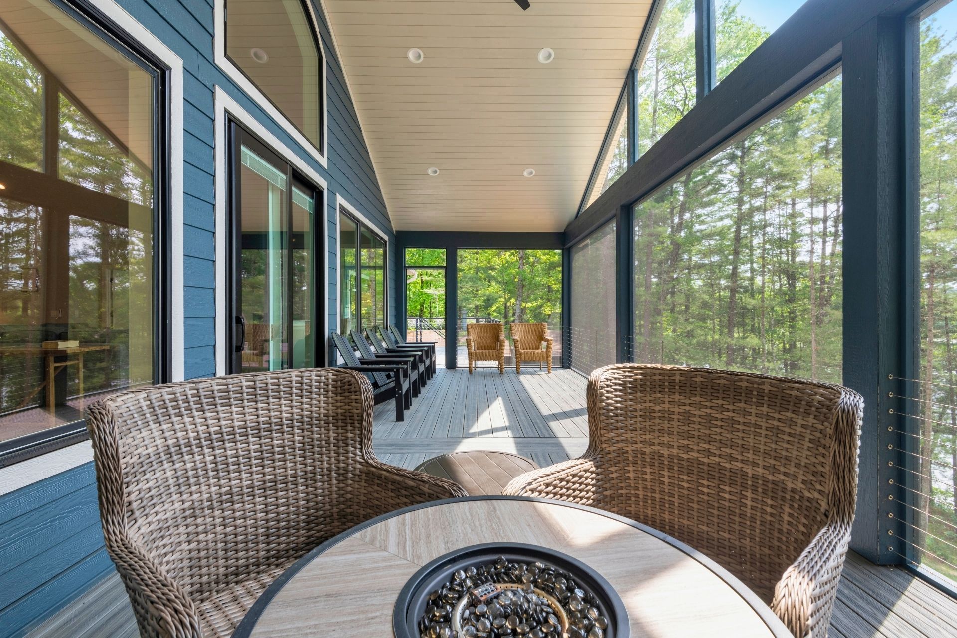 A screened in porch with a table and chairs and a fire pit.