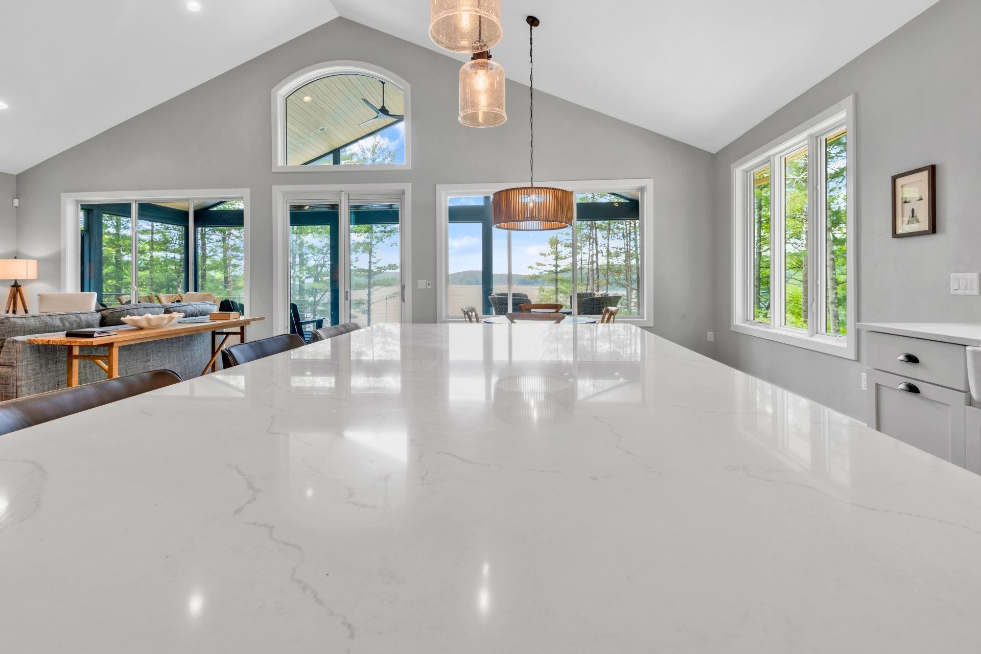 A kitchen with a large white counter top and a lot of windows.
