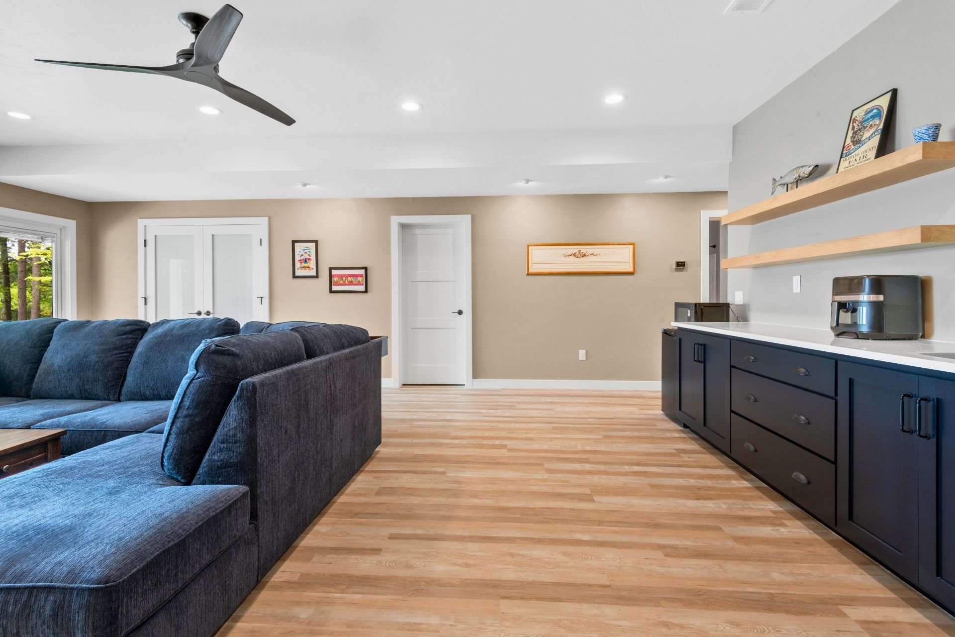 A living room with a blue sectional couch and a ceiling fan.