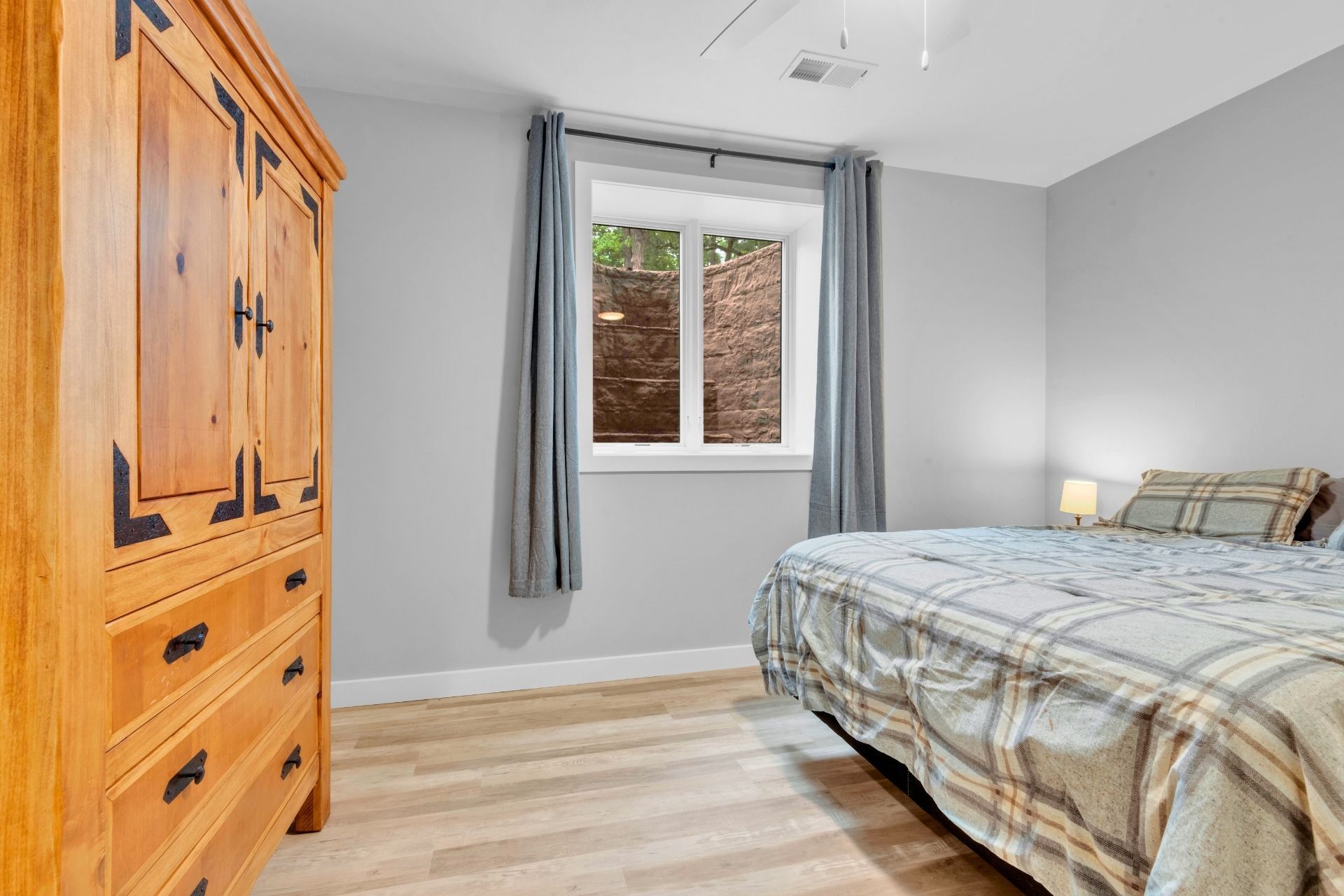 A bedroom with a bed , dresser , and window.
