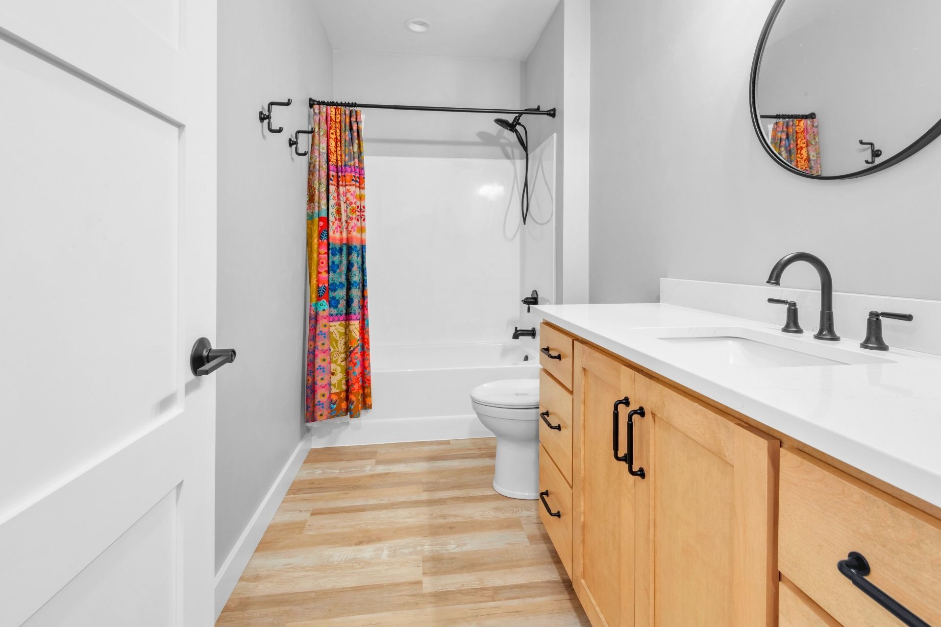 A bathroom with a toilet , sink , mirror and shower curtain.