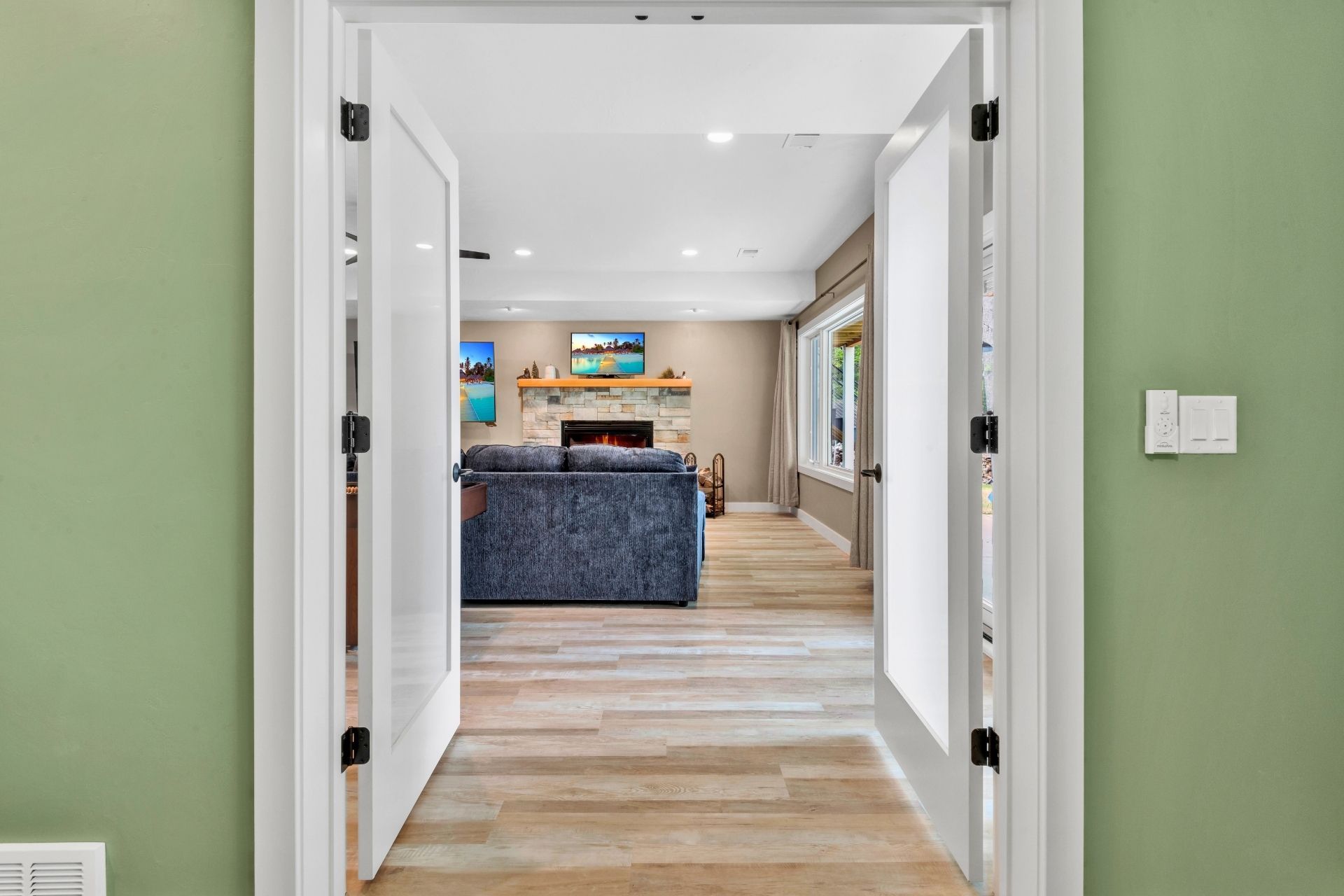 A hallway leading to a living room with a couch and fireplace.