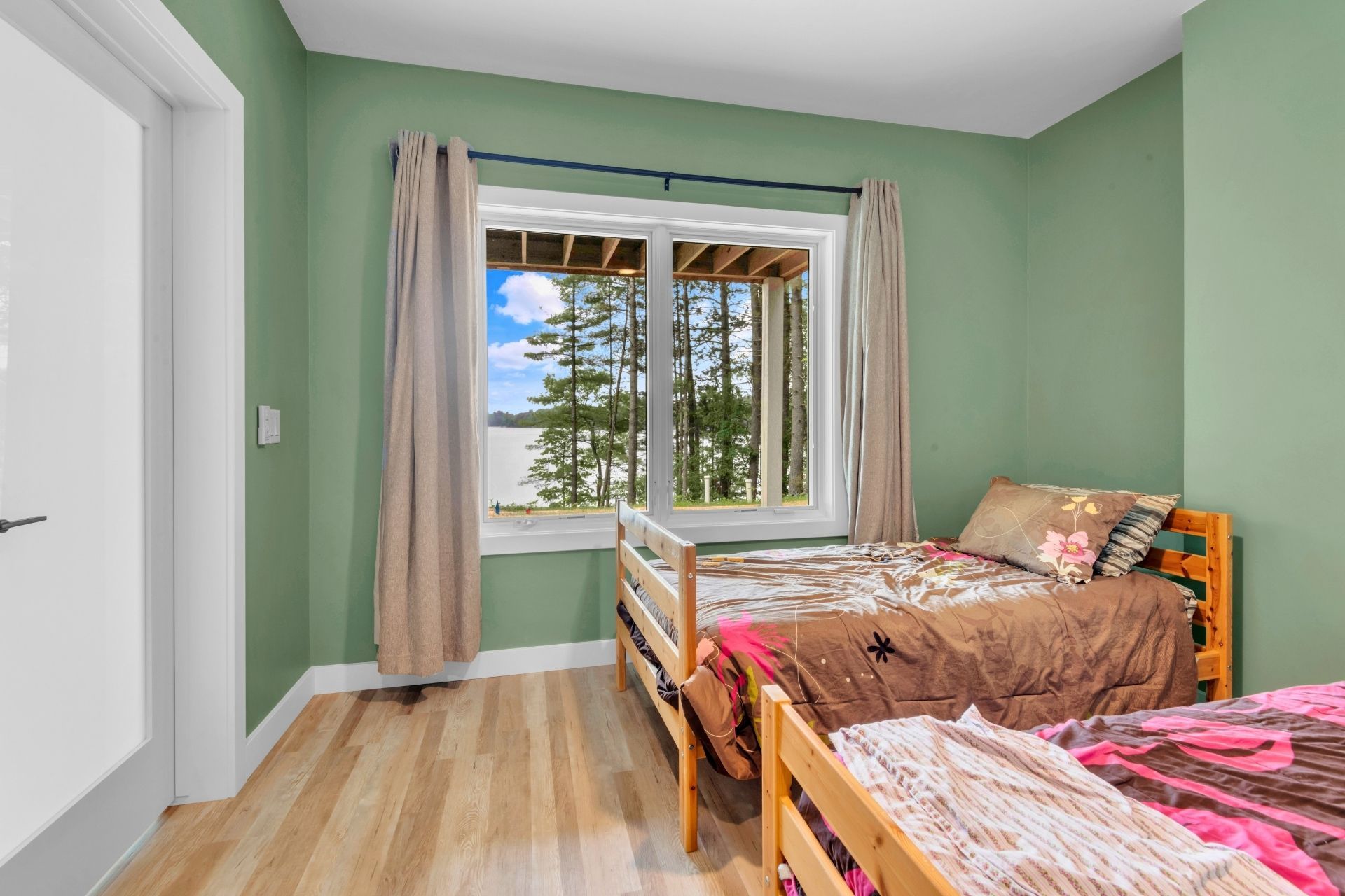 A bedroom with two beds and a large window.