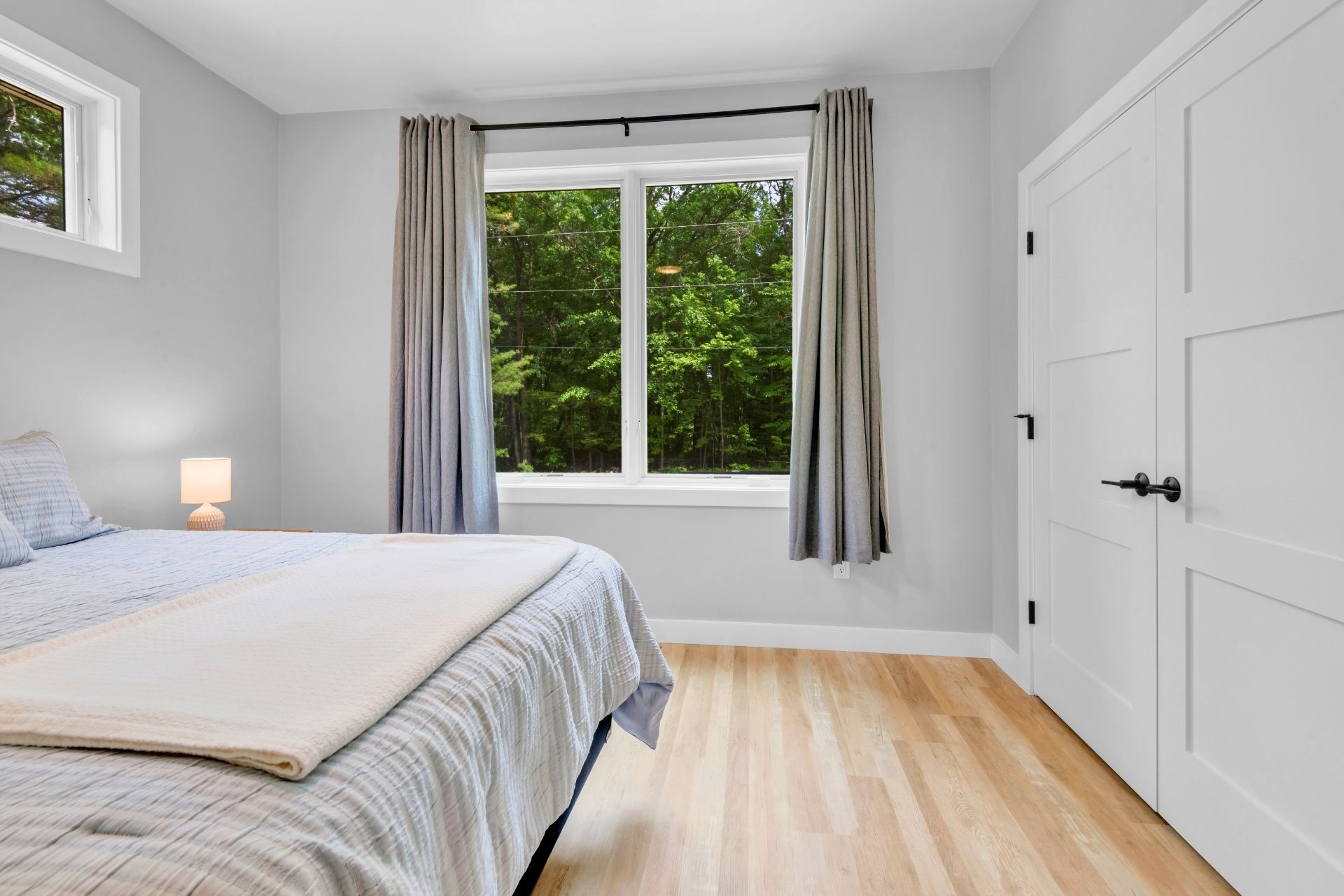A bedroom with a bed and a window with trees in the background.