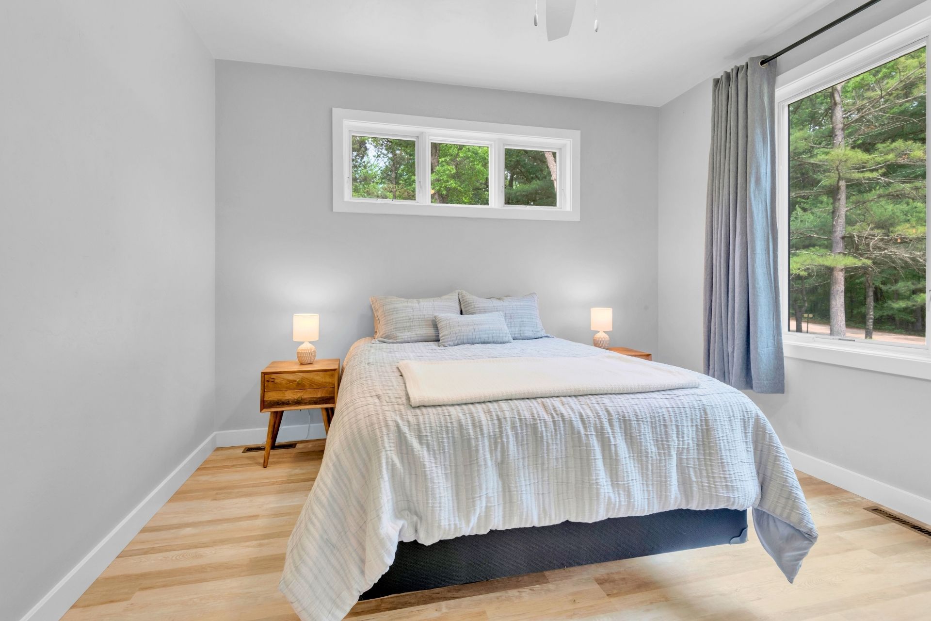 A bedroom with a bed , two nightstands , and a window.