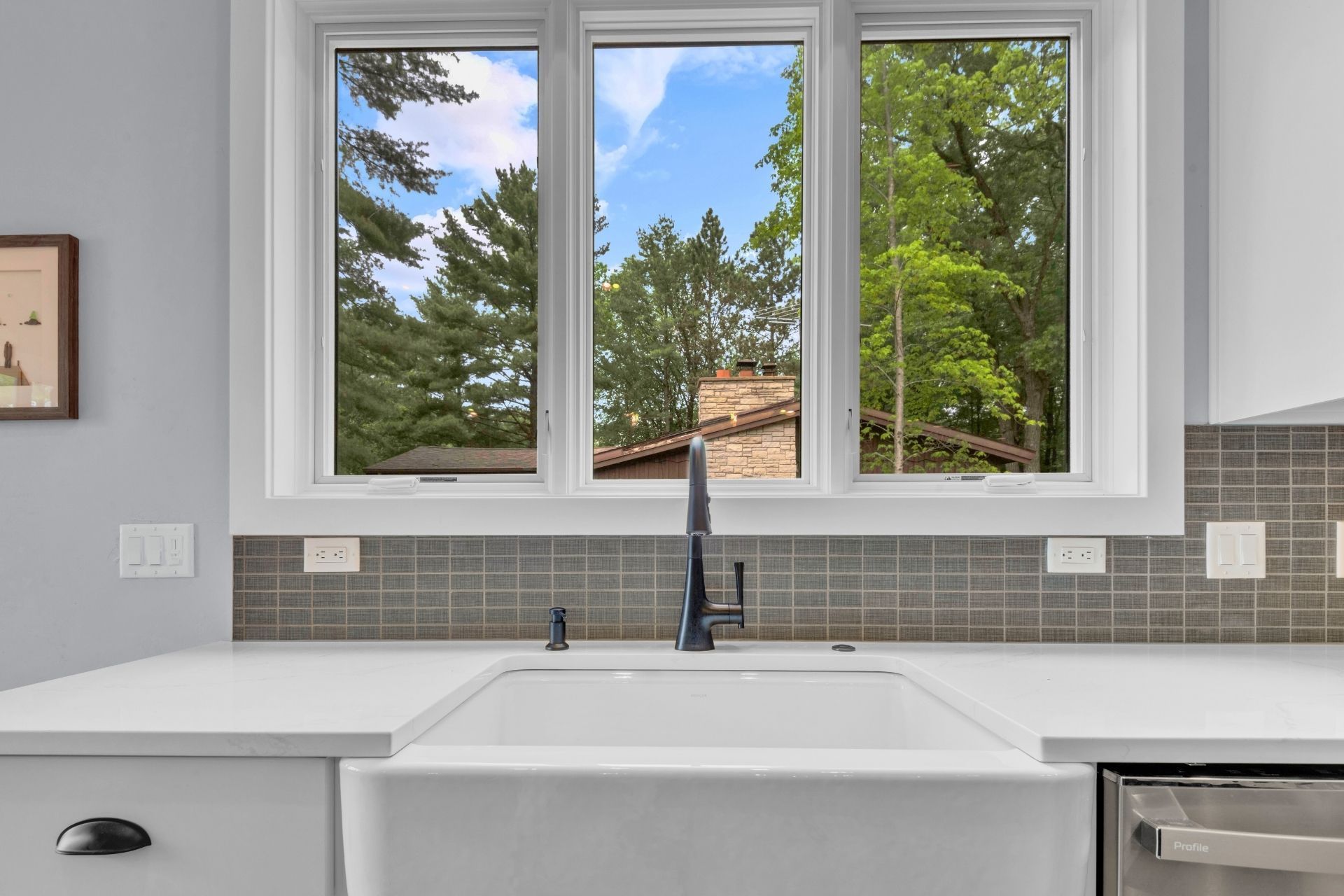 A kitchen with a sink and a window with a view of trees.