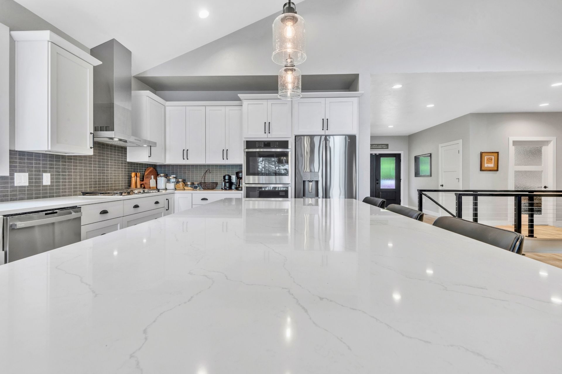 A kitchen with white cabinets , stainless steel appliances , and a large island.