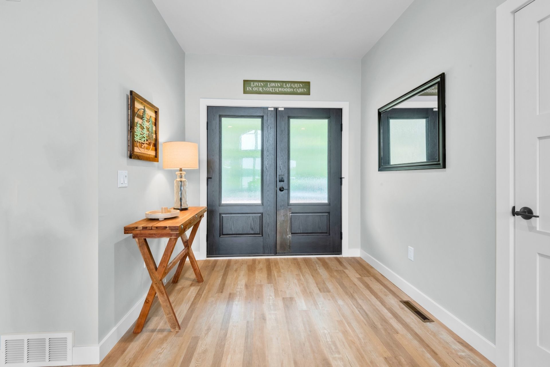 A hallway with hardwood floors and a black door.