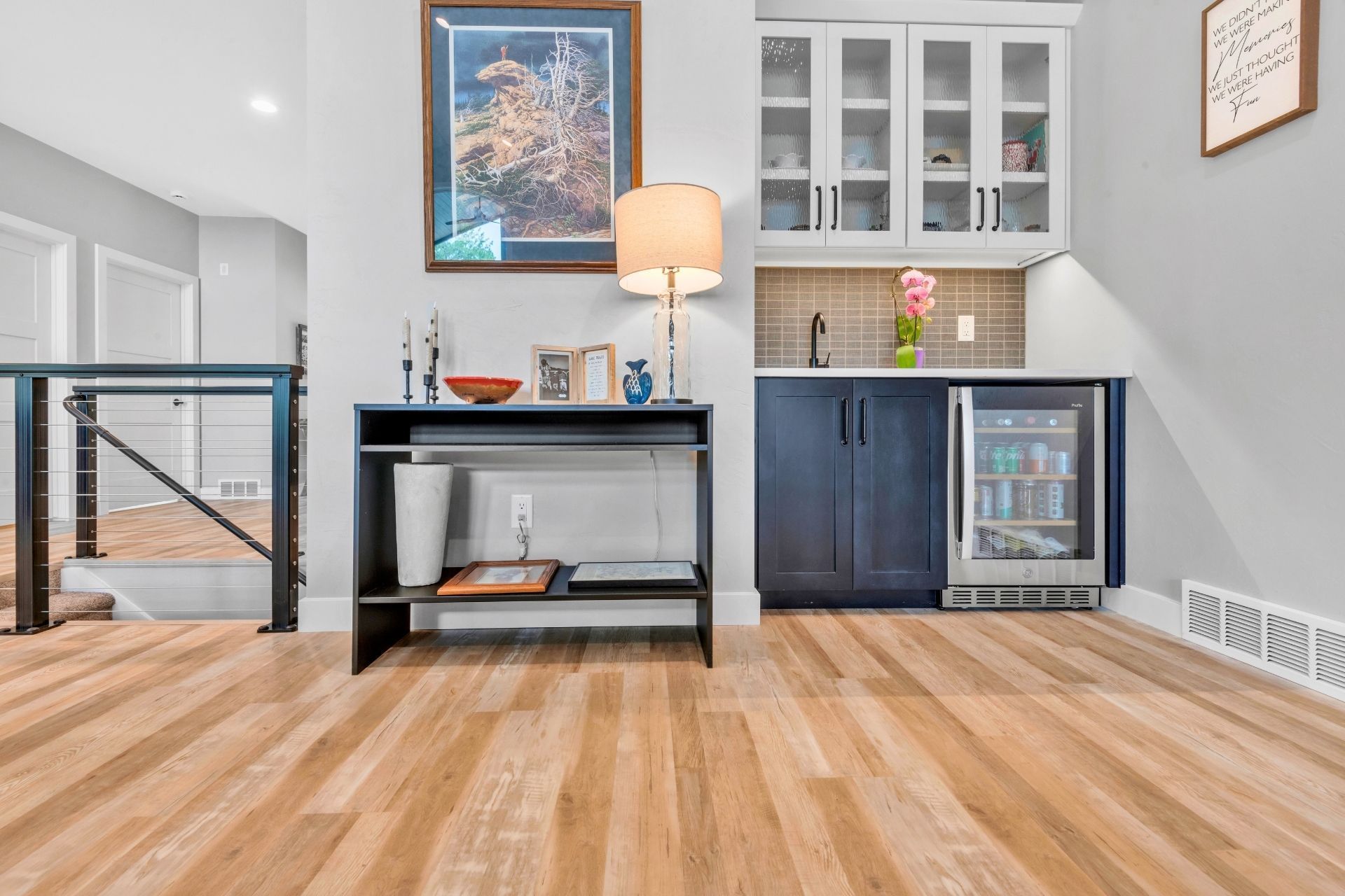 A living room with hardwood floors , a table and a refrigerator.