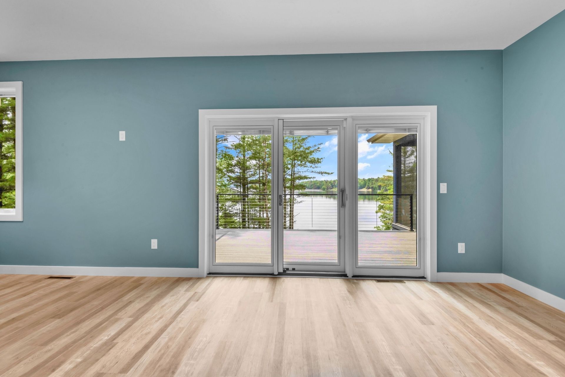 An empty room with hardwood floors and sliding glass doors