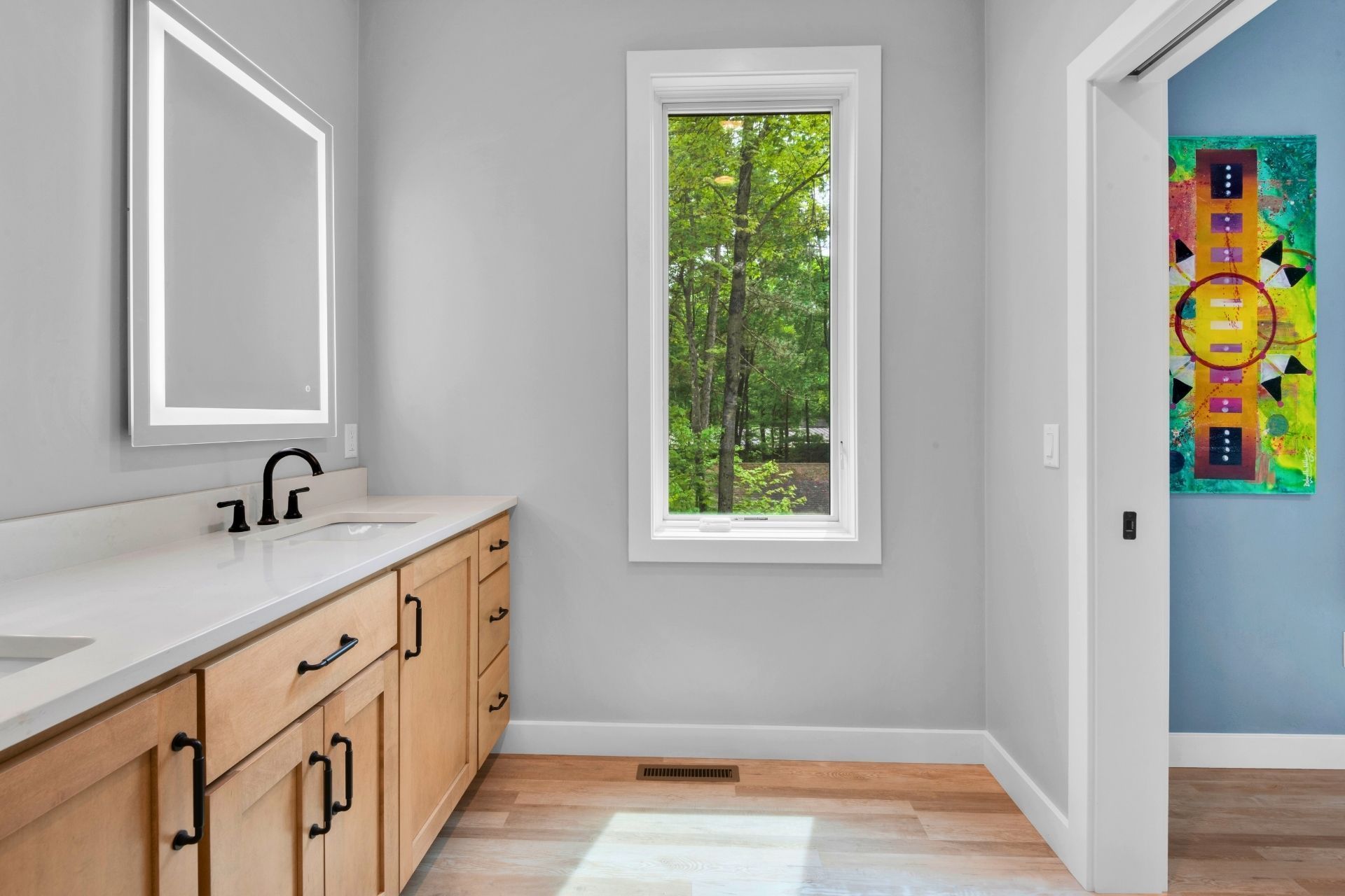 A bathroom with a sink , mirror and window.