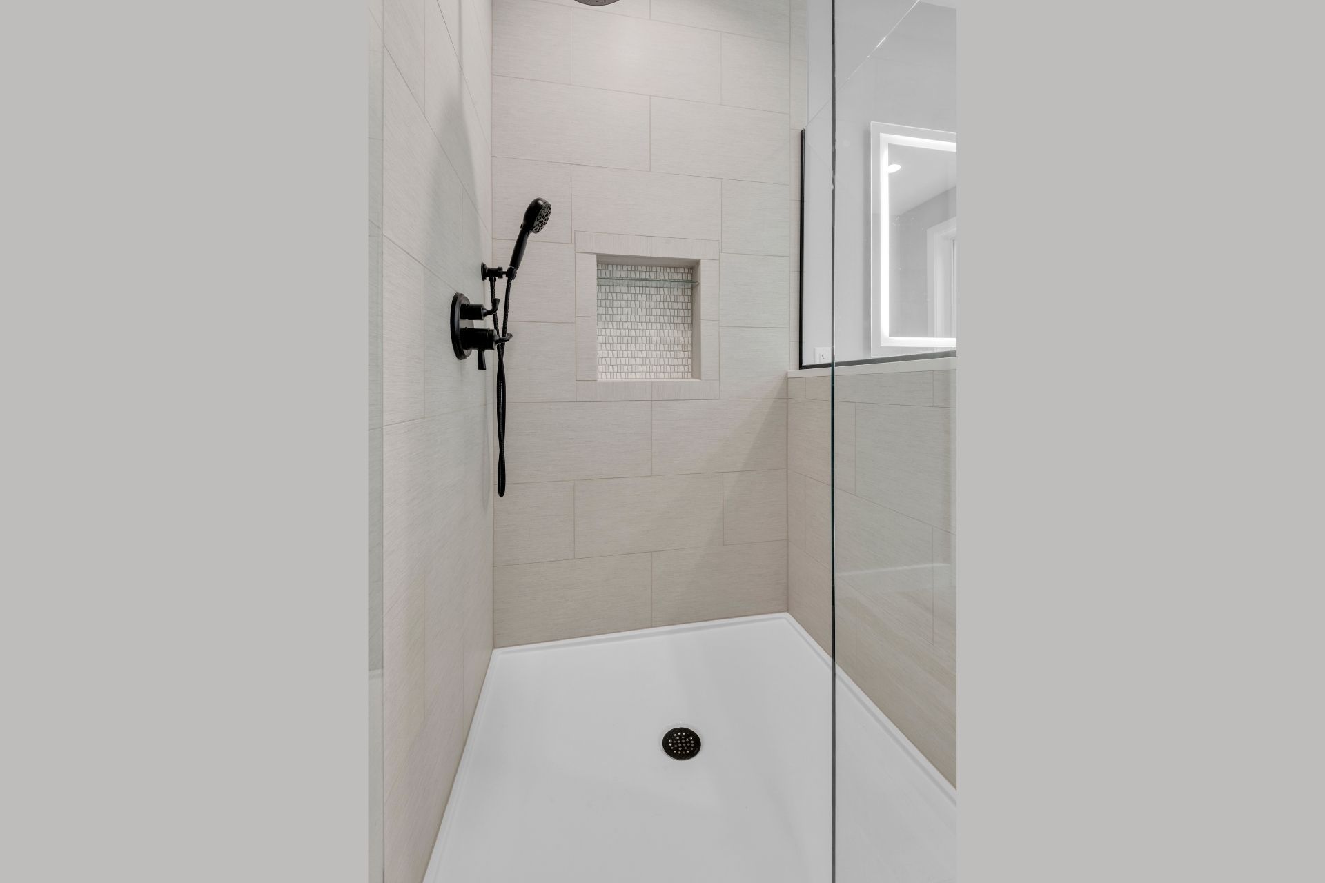 A bathroom with a walk in shower with a glass door and a shower head.