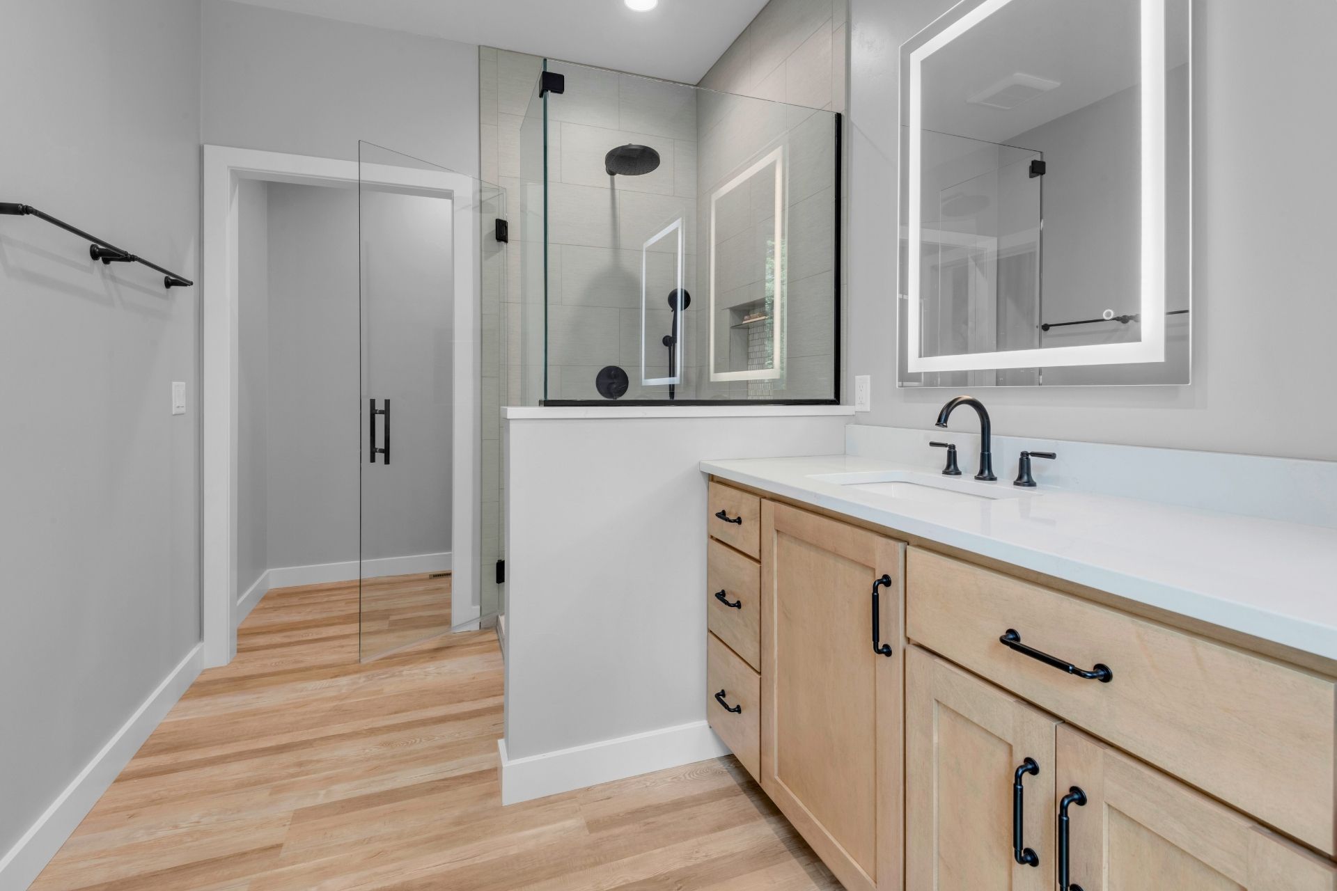 A bathroom with a sink , mirror and walk in shower.