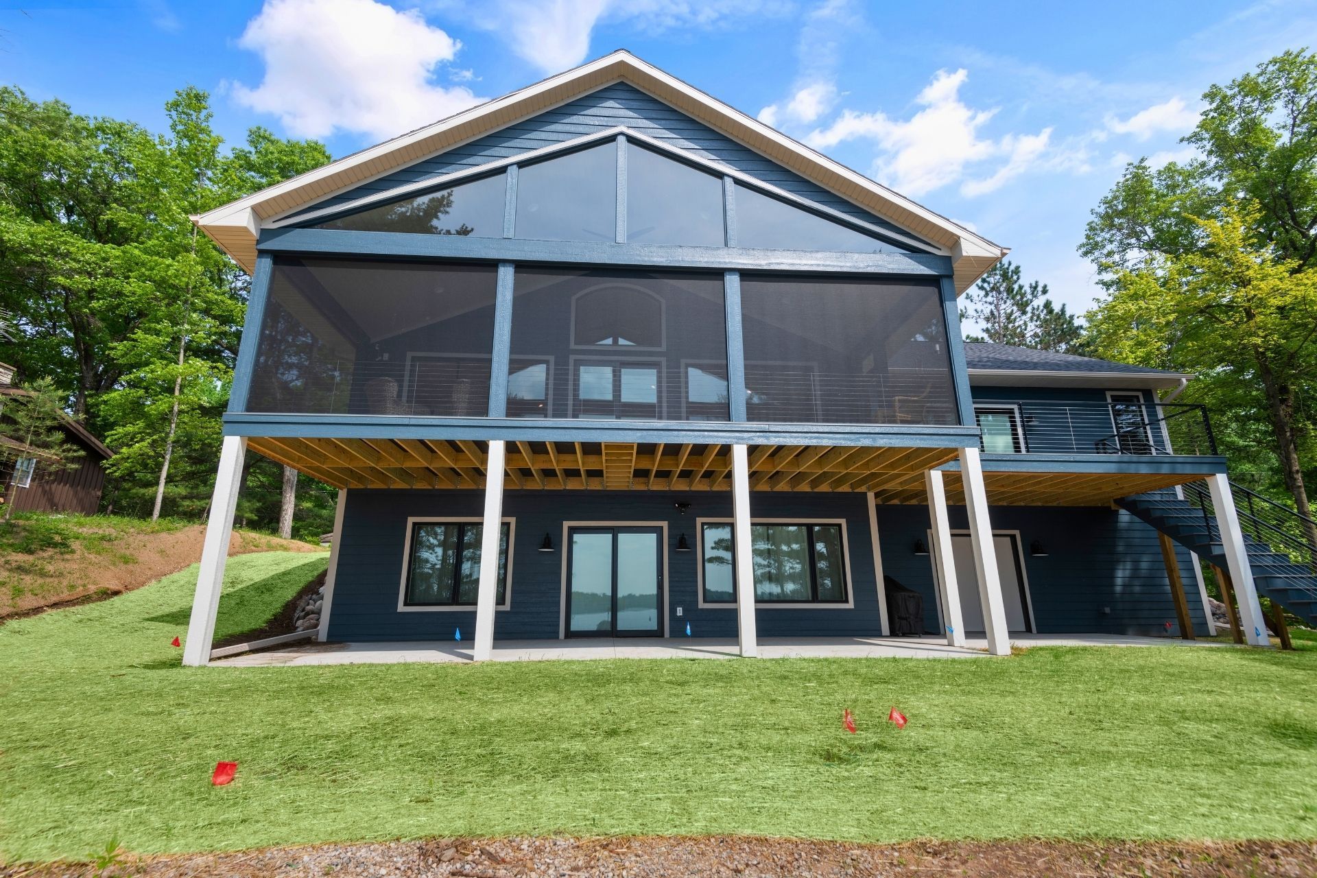 A large house with a screened in porch is sitting on top of a grassy hill.