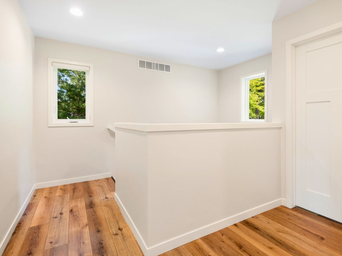 An empty room with hardwood floors and white walls.