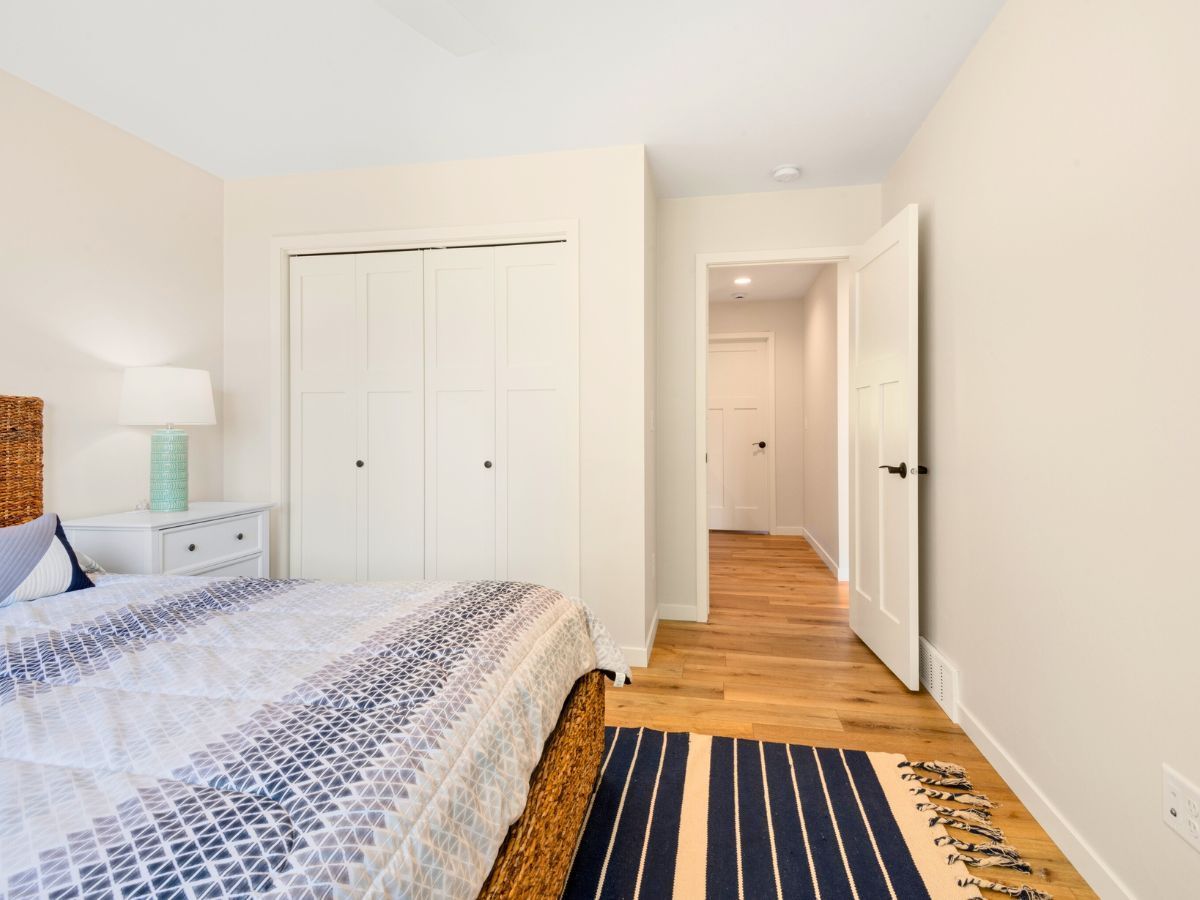 A bedroom with a bed , rug , lamp and closet.